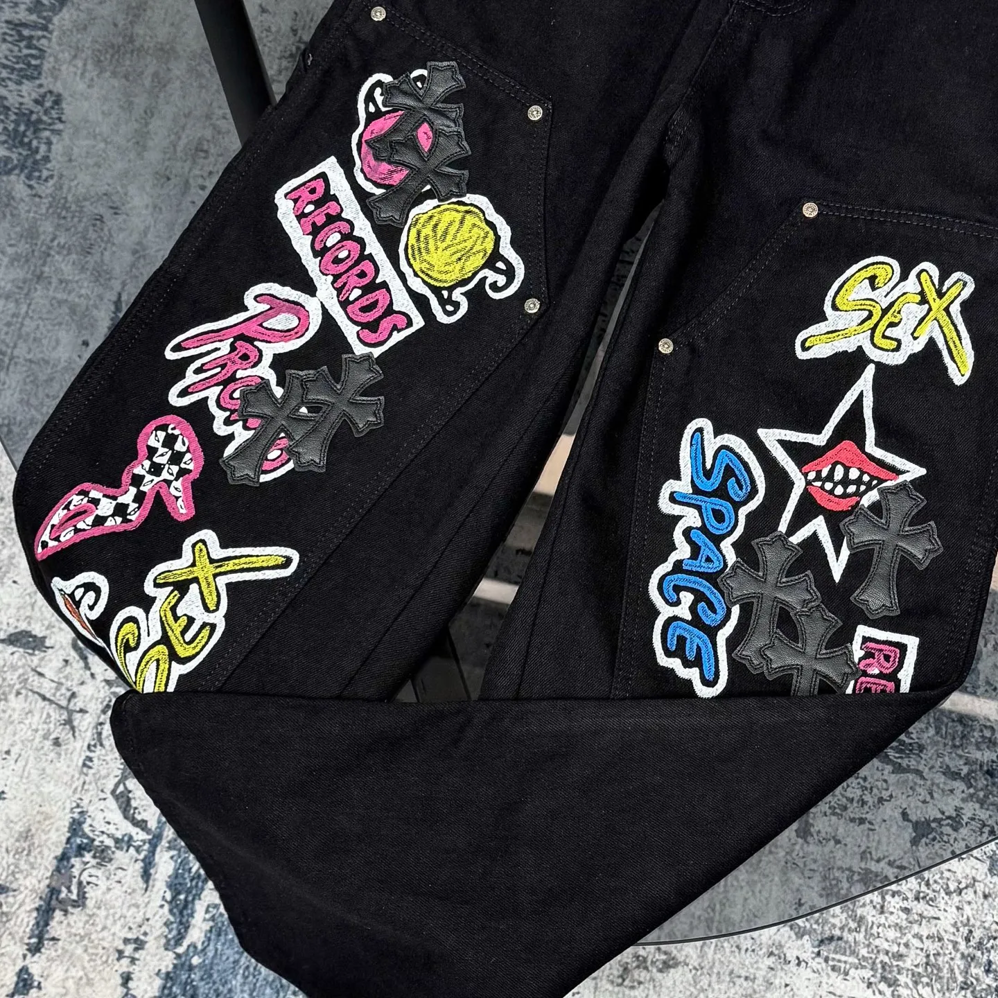 P260 Chrome Hearts Chrome Hearts black multi-element graffiti overalls Chrome Hearts clothing creative director Mattyboy Mattyboy, whose real name is Matt DiGiacomo, is a graffiti artist with a non-school background. He started to serve as the creative director of the Chrome Hearts clothing series in 2018. Since then, Chrome Hearts, which has been injected with young blood, has become popular again. Popular clothing and leather goods, especially the vintage trousers modified product line, must be pre-ordered in stores around the world. Especially patterns like Checker Ball, Checker Eyes and Smiling Lips. The fictional record company logo "SexRecords" often appears in his works, forming his unique style. "I hate humanity, but I love art. Before the end of my life, I just want to do my best to create." ----Matty Boy Mattyboy and vrigil Abloh are also very close. They are both ICONs who bring street culture into luxury accessories. Via.MattyBoy90 (IG) Size: 28/30/32/34/36 Waist: 69/74/79/84/89 Knee circumference: 50/51.5/53/54.5/56 Pants length: 102/104/106/108/110